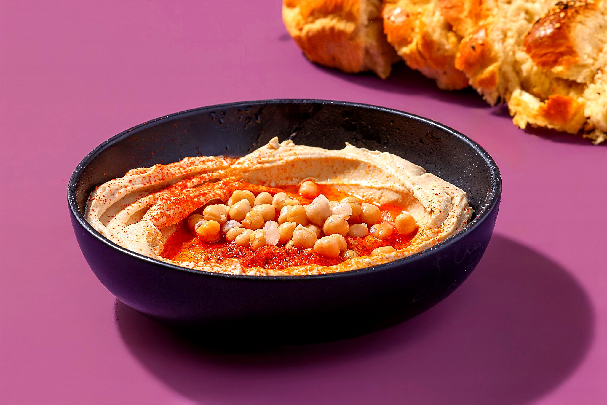 Bowl of creamy hummus with chickpeas and warm challah