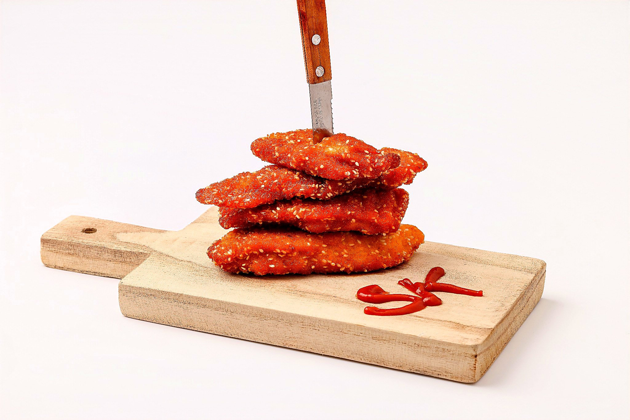 Stack of golden sesame schnitzel on a wooden board